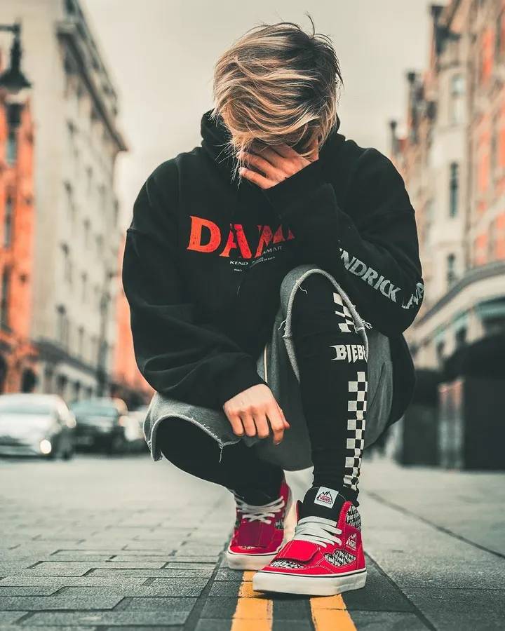 A Man Crouching Down On The Street