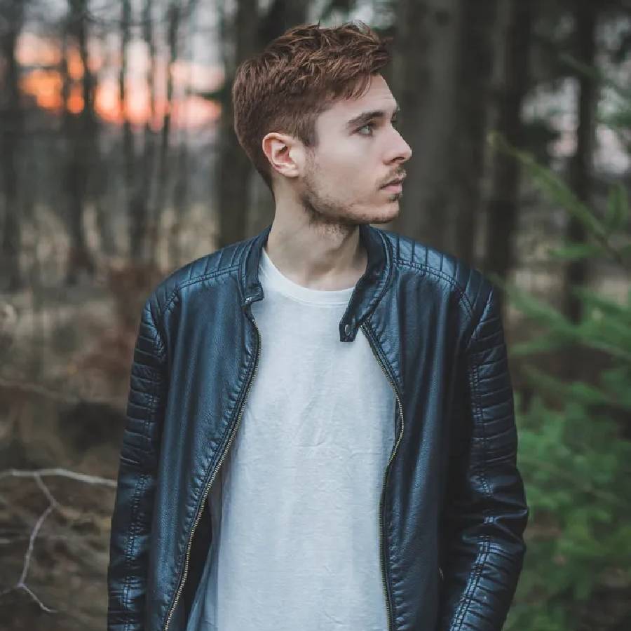 A Boy In A Leather Jacket Standing In The Woods